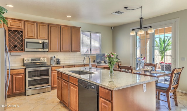 kitchen with visible vents, decorative backsplash, appliances with stainless steel finishes, brown cabinetry, and a sink