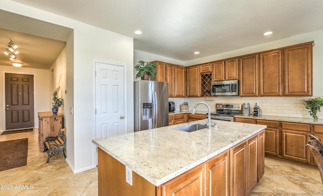 kitchen featuring stainless steel appliances, brown cabinets, a sink, and tasteful backsplash