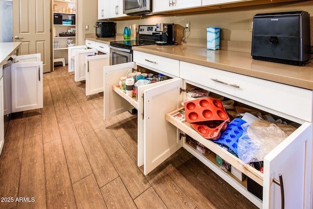 kitchen with stainless steel appliances, light wood finished floors, light countertops, and white cabinets