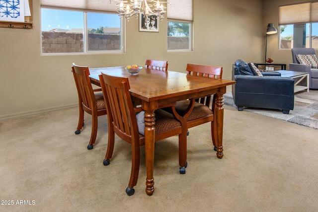 dining area featuring baseboards, a chandelier, and light colored carpet