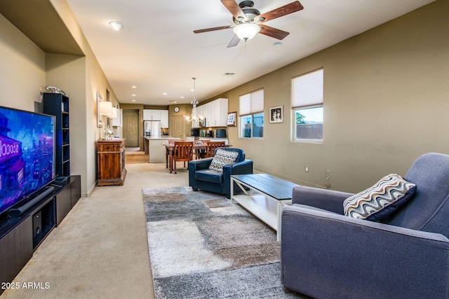 living area with light carpet, recessed lighting, a ceiling fan, and baseboards