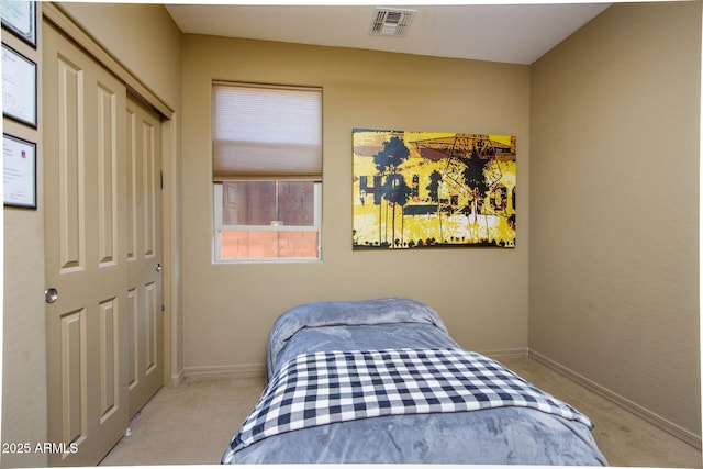 bedroom with a closet, light colored carpet, visible vents, and baseboards