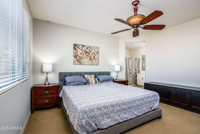 bedroom featuring light carpet, baseboards, a ceiling fan, and ensuite bathroom