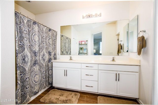 bathroom featuring wood tiled floor, a sink, and double vanity