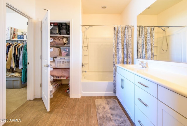 bathroom featuring wood finished floors, shower / bath combo, a walk in closet, and vanity