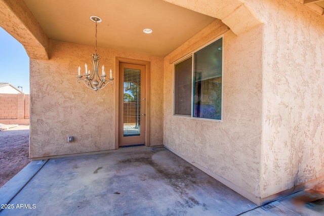 property entrance with a patio area, fence, and stucco siding