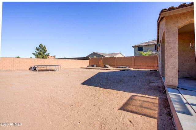 view of yard with a trampoline and a fenced backyard