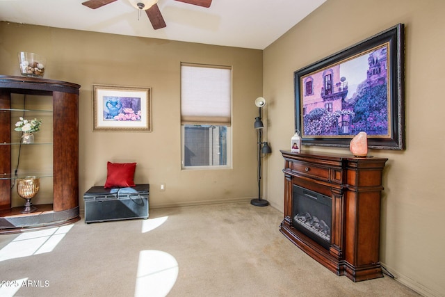 interior space featuring a ceiling fan, a glass covered fireplace, light colored carpet, and baseboards