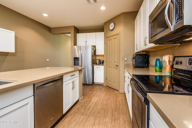 kitchen featuring recessed lighting, stainless steel appliances, light wood-style floors, white cabinets, and light countertops