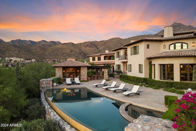 pool at dusk featuring a mountain view and a patio