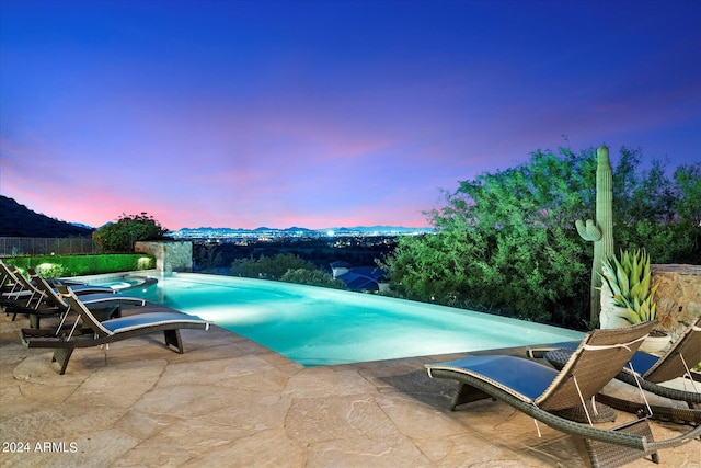 pool at dusk with a patio area