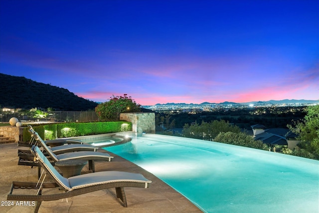 pool at dusk with a mountain view and an in ground hot tub