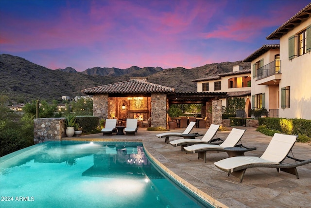 pool at dusk with a patio and a mountain view