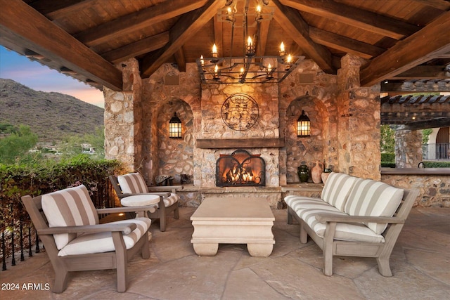 patio terrace at dusk with an outdoor stone fireplace and a mountain view