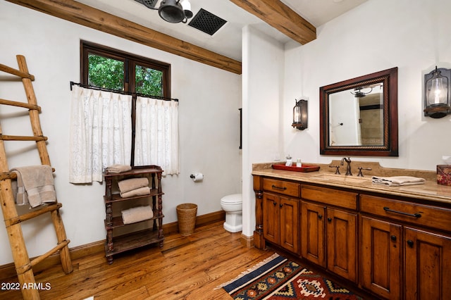 bathroom featuring vanity, toilet, hardwood / wood-style floors, and beam ceiling