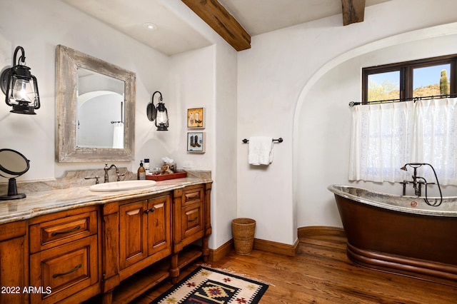 bathroom with vanity, hardwood / wood-style flooring, a bathing tub, and beam ceiling