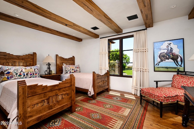 bedroom with wood-type flooring and beam ceiling