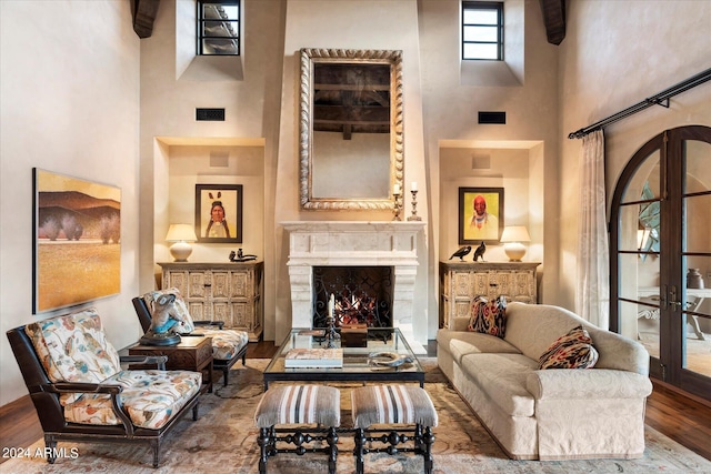 living room with a fireplace, french doors, hardwood / wood-style flooring, and a high ceiling