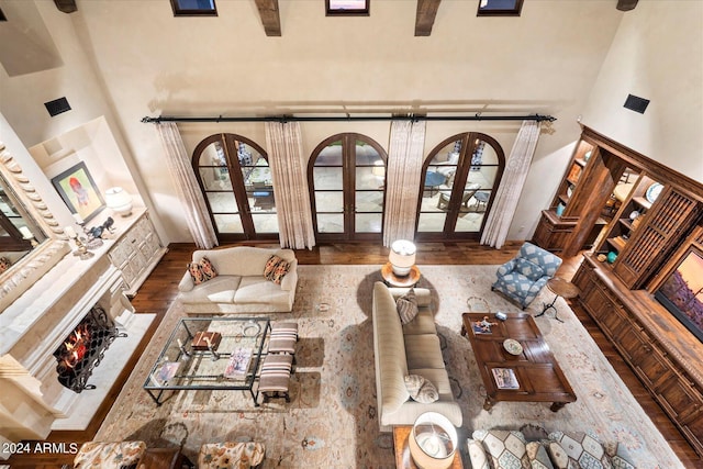 living room with french doors, hardwood / wood-style flooring, beam ceiling, and a high ceiling