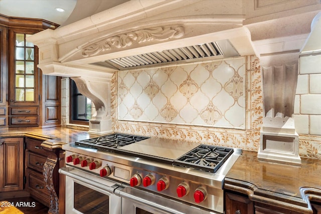 kitchen featuring custom range hood, range with two ovens, and decorative backsplash