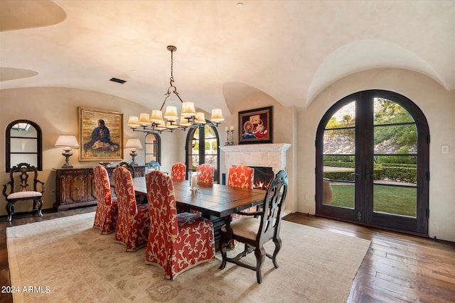 dining room with lofted ceiling, a wealth of natural light, an inviting chandelier, and light hardwood / wood-style floors