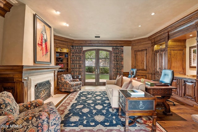 living room with built in features, ornamental molding, light wood-type flooring, and french doors