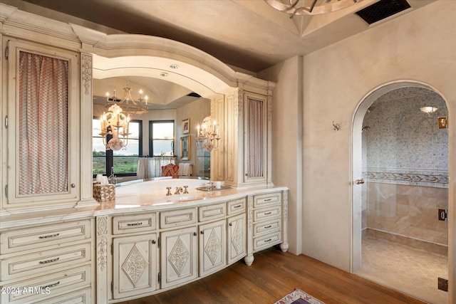 bathroom with hardwood / wood-style floors, a shower with door, an inviting chandelier, and vanity