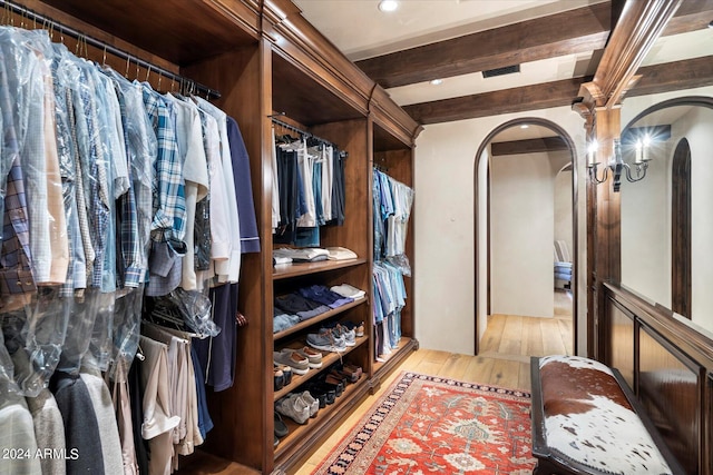 walk in closet with beamed ceiling and light hardwood / wood-style flooring