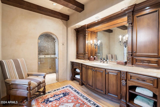 bathroom with vanity, a tile shower, hardwood / wood-style flooring, and beamed ceiling