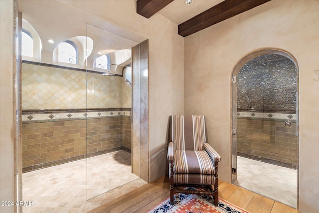 bathroom with beamed ceiling, hardwood / wood-style flooring, and tiled shower