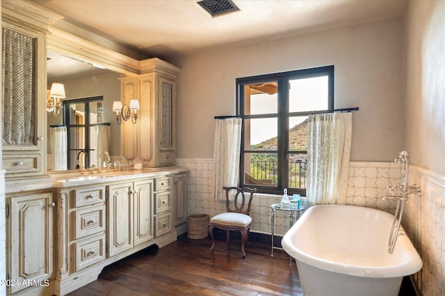 bathroom with a tub, wood-type flooring, vanity, and tile walls