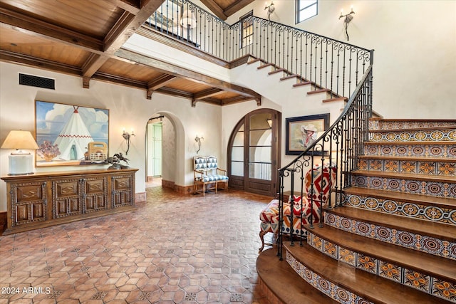 foyer entrance with wooden ceiling, beamed ceiling, a towering ceiling, and coffered ceiling