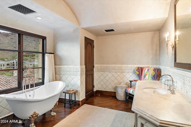 bathroom with a tub, vaulted ceiling, vanity, tile walls, and hardwood / wood-style flooring