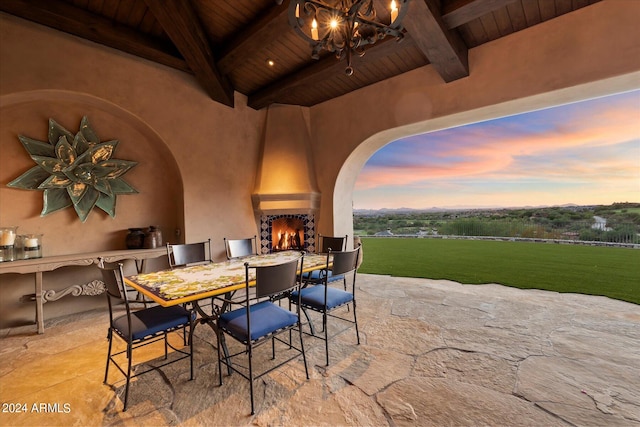 patio terrace at dusk with an outdoor kitchen and a large fireplace