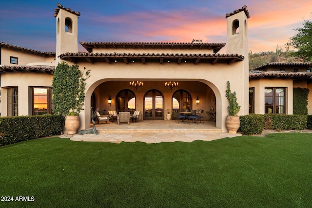 back house at dusk featuring a lawn, an outdoor hangout area, and a patio area