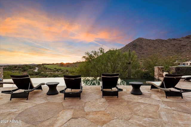 patio terrace at dusk featuring a mountain view