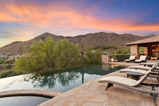 pool at dusk with a mountain view and a patio