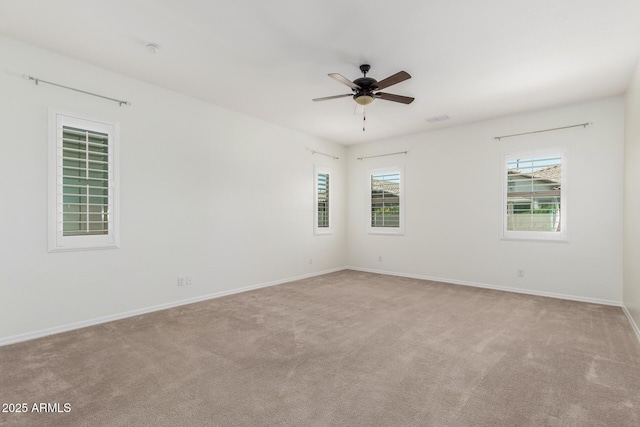 carpeted empty room with ceiling fan and baseboards