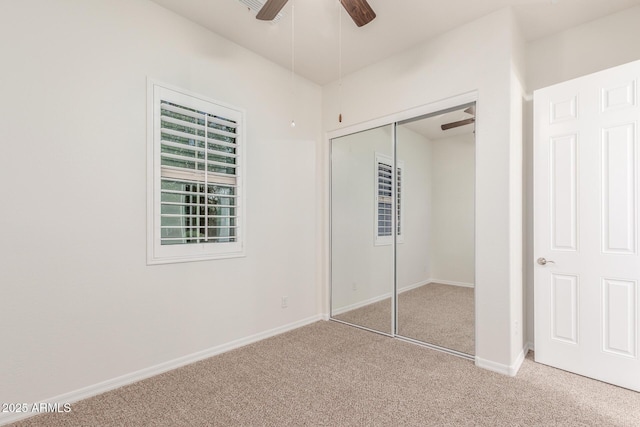 unfurnished bedroom with carpet, a closet, baseboards, and a ceiling fan