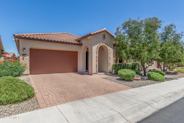 mediterranean / spanish-style home featuring stucco siding, an attached garage, decorative driveway, and a tile roof