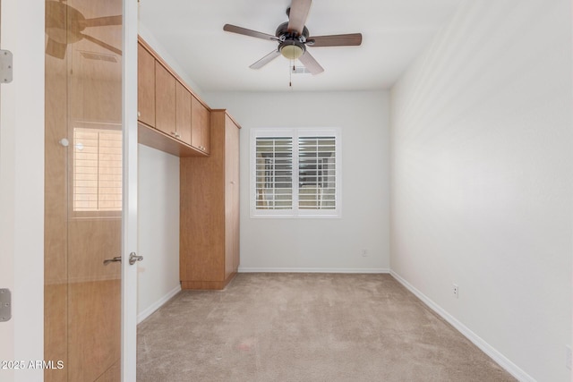 unfurnished bedroom with light colored carpet, baseboards, and a ceiling fan