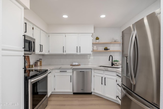 kitchen with a sink, appliances with stainless steel finishes, white cabinets, and tasteful backsplash