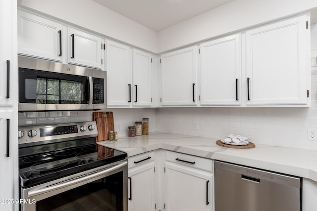 kitchen featuring white cabinets, backsplash, appliances with stainless steel finishes, and light stone counters