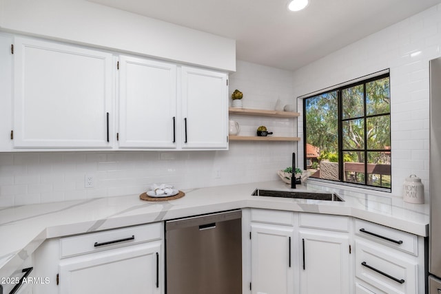 kitchen featuring stainless steel dishwasher, white cabinetry, decorative backsplash, and a sink