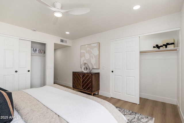 bedroom featuring visible vents, a ceiling fan, baseboards, and wood finished floors