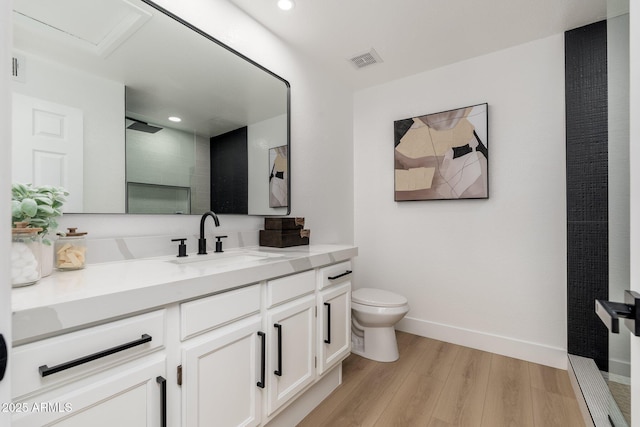 bathroom with visible vents, vanity, a shower with door, wood finished floors, and toilet
