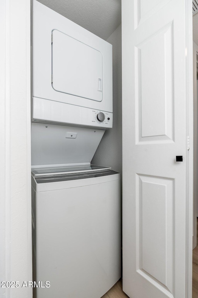 washroom featuring stacked washer and clothes dryer and laundry area