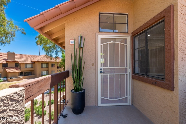 view of exterior entry with stucco siding and a balcony