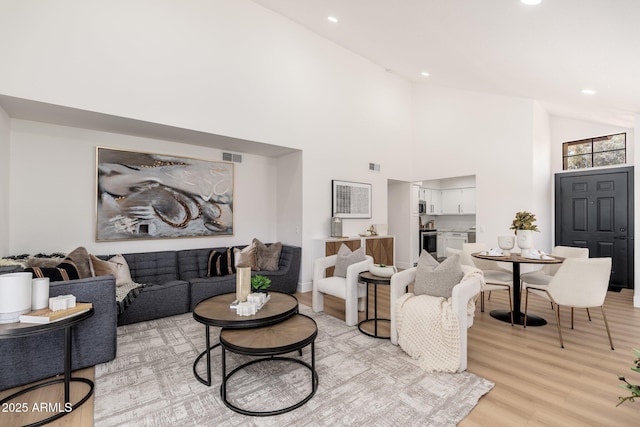 living area with recessed lighting, high vaulted ceiling, light wood finished floors, and visible vents