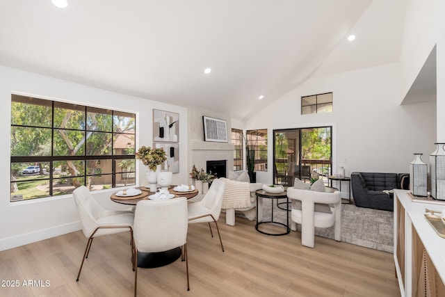 dining area featuring recessed lighting, light wood-type flooring, a wealth of natural light, and a fireplace